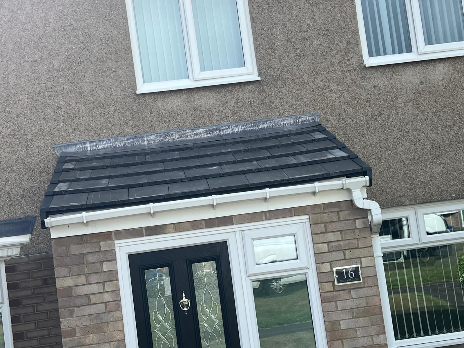 Gray house with black door and roof. White trim, brick facade.