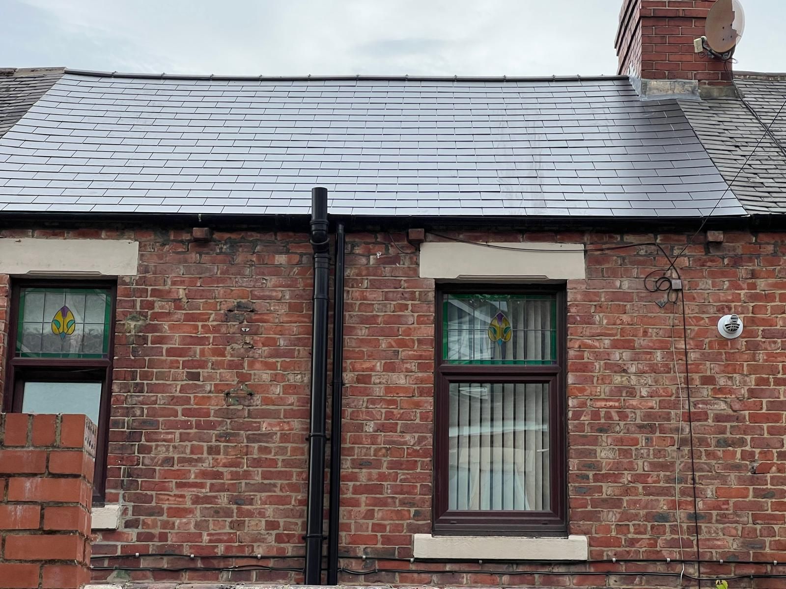 Brick building with dark roof, windows, and a chimney.