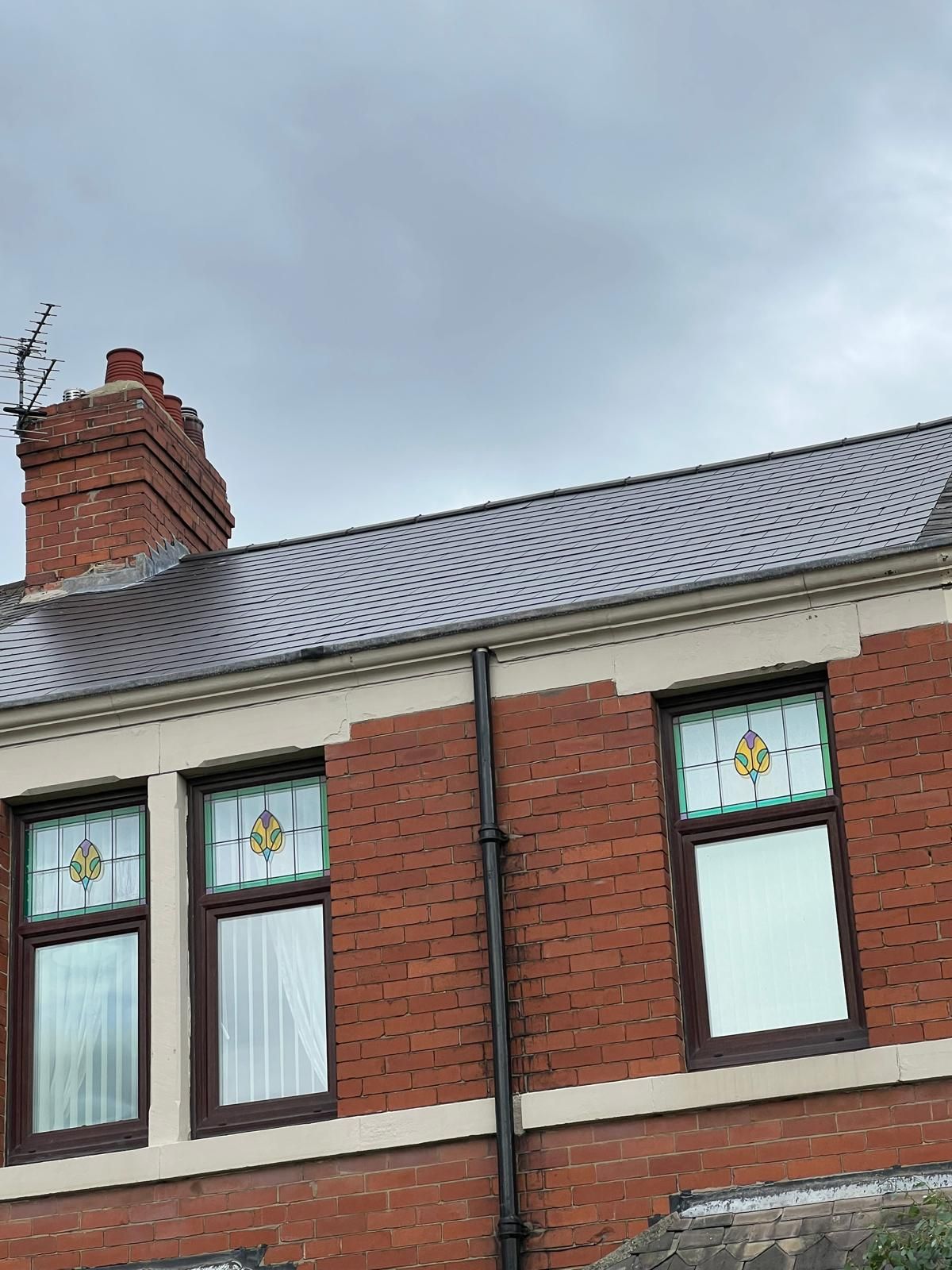 Red brick building with stained glass windows under a gray roof.
