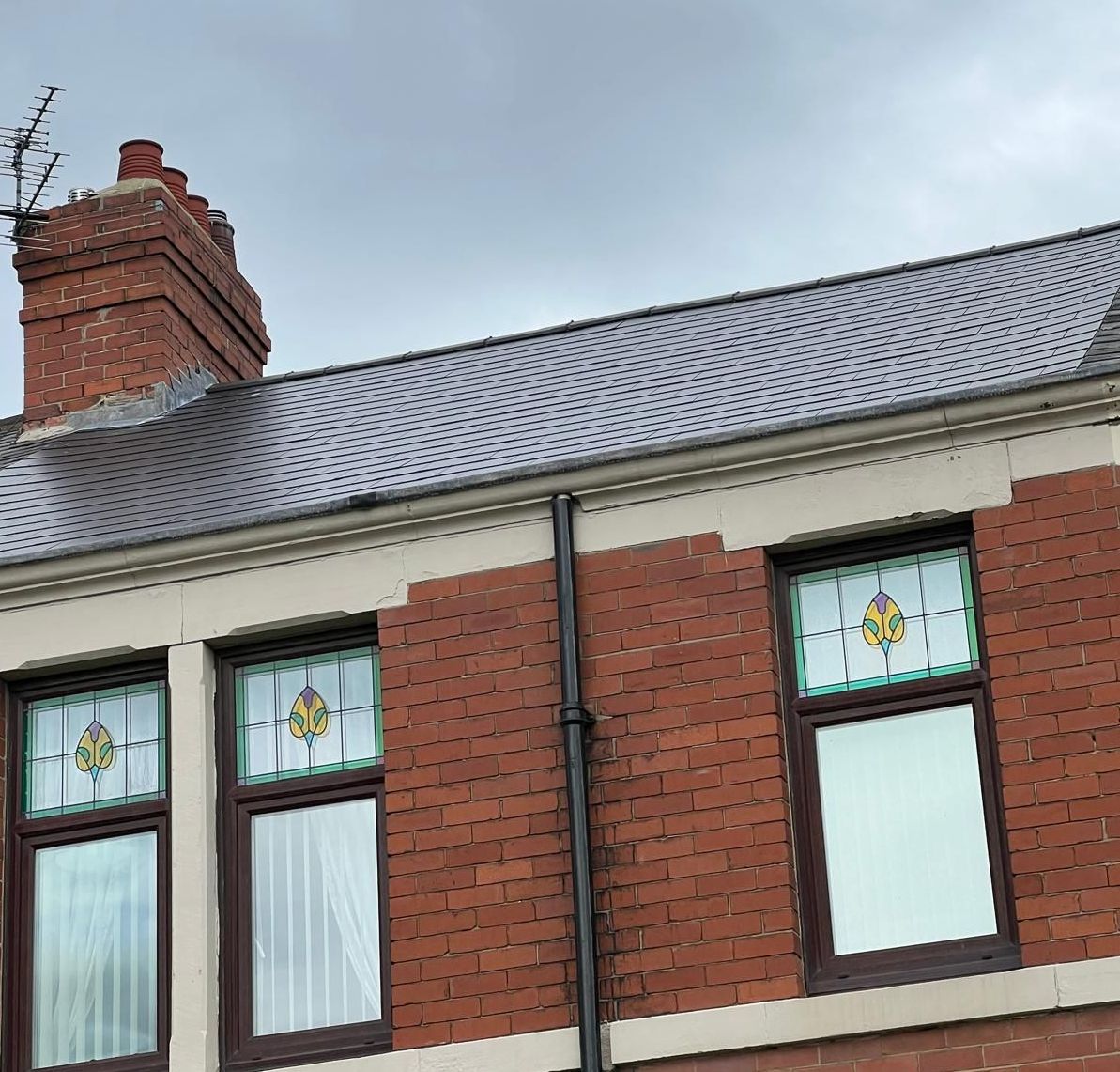 Red brick building with stained glass windows under a grey roof.