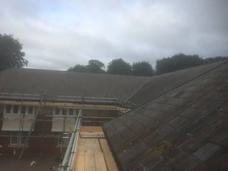 Gray overcast sky above a building with a dark weathered roof and scaffolding.