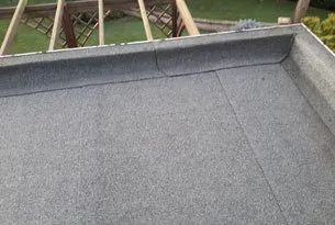 Flat, gray roofing material with a raised edge, bordering a wooden framework.