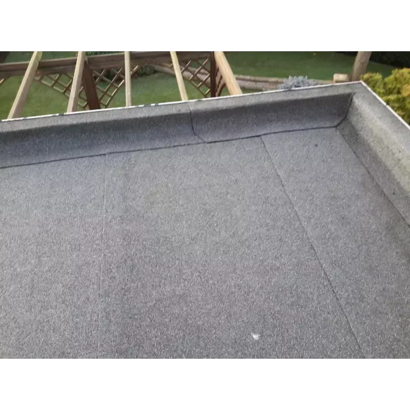 Flat gray roofing with a built-up edge, partially visible wooden frame structure in the background.