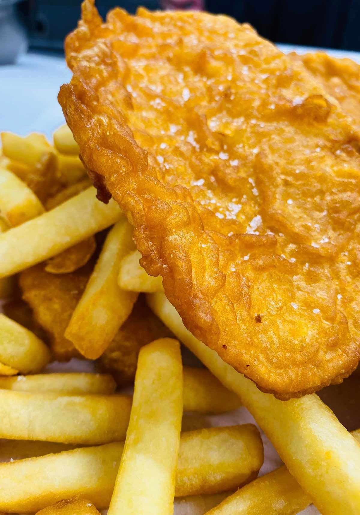 A Close Up of a Piece of Fried Fish and French Fries on a Plate — Cedar Park Fish & Chips In Taranganba, QLD