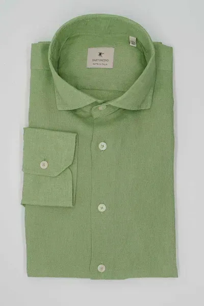 Una camicia verde è appoggiata su una superficie bianca.