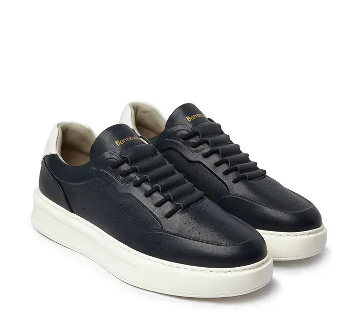 Un paio di scarpe da ginnastica nere con suola bianca su sfondo bianco.