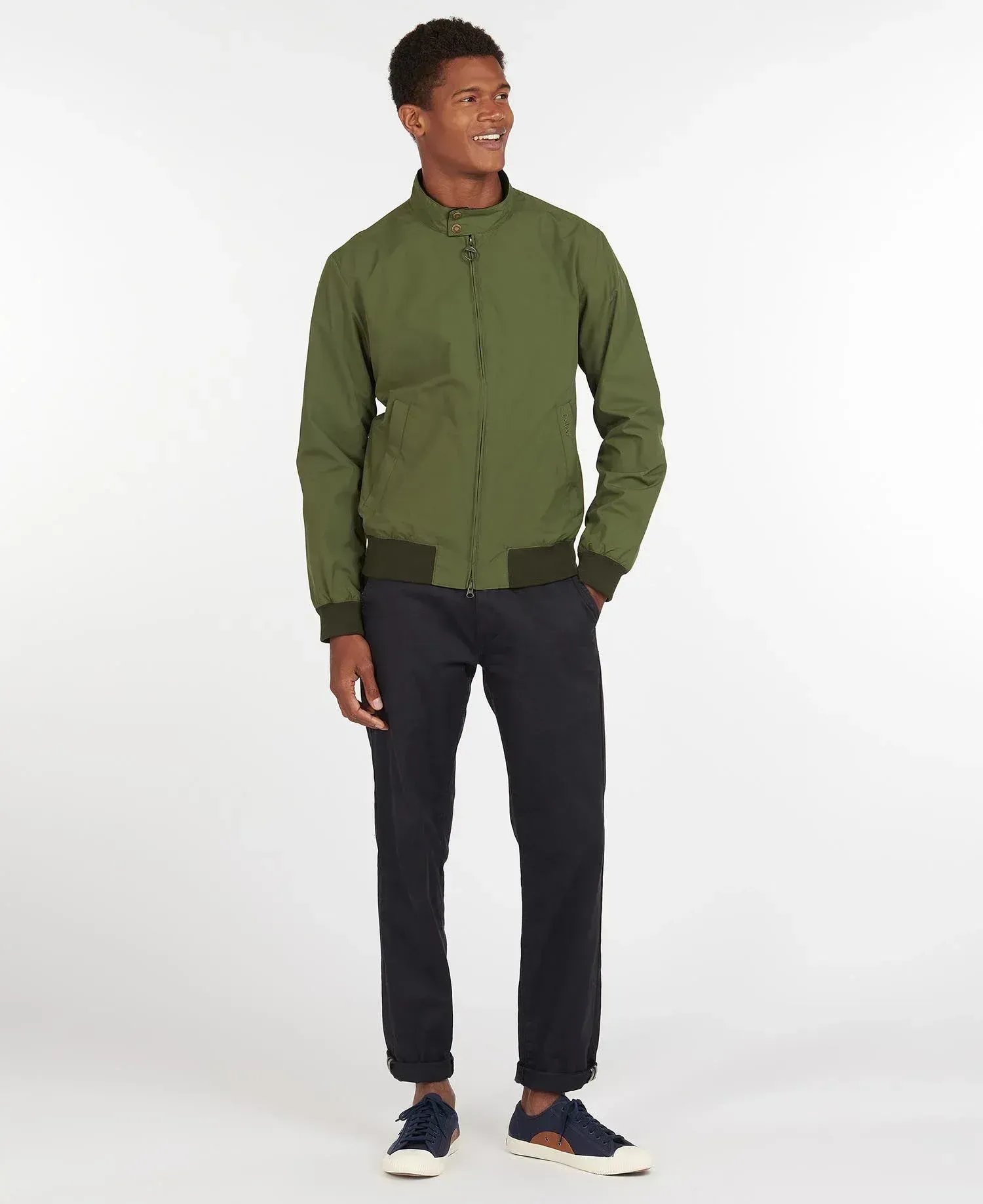 Un uomo indossa una giacca verde e pantaloni neri.