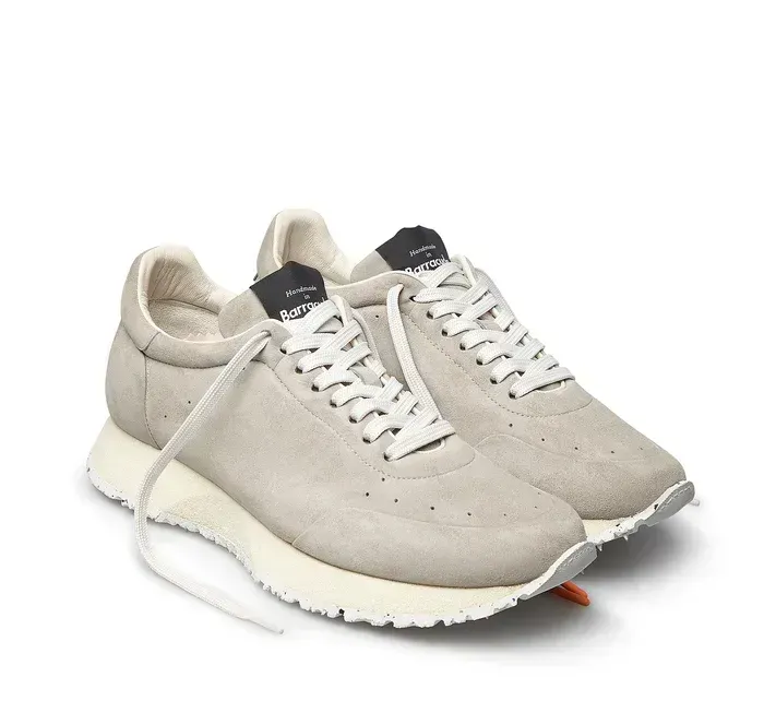 Un paio di scarpe da ginnastica bianche con lacci bianchi su sfondo bianco