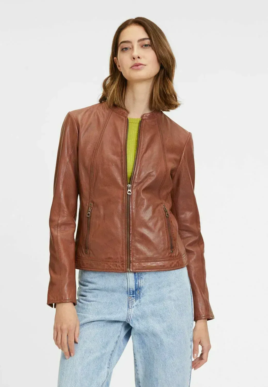 Una donna indossa una giacca di pelle marrone e jeans.