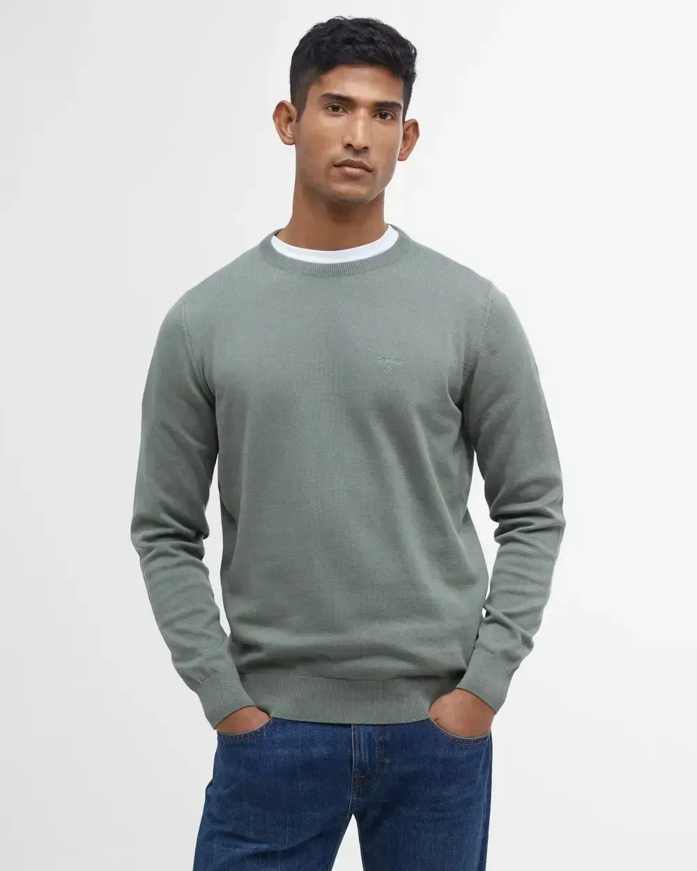 Un uomo che indossa un maglione verde e jeans blu