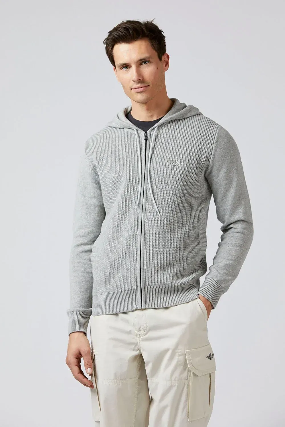 Un uomo che indossa una felpa grigia con cappuccio e pantaloni bianchi