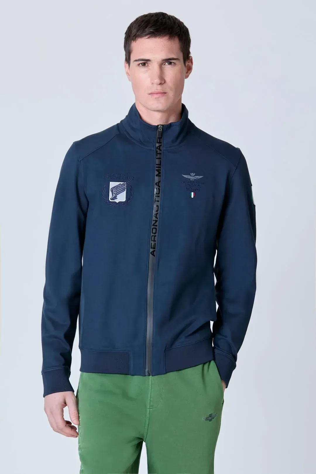 Un uomo che indossa una giacca blu e pantaloni verdi