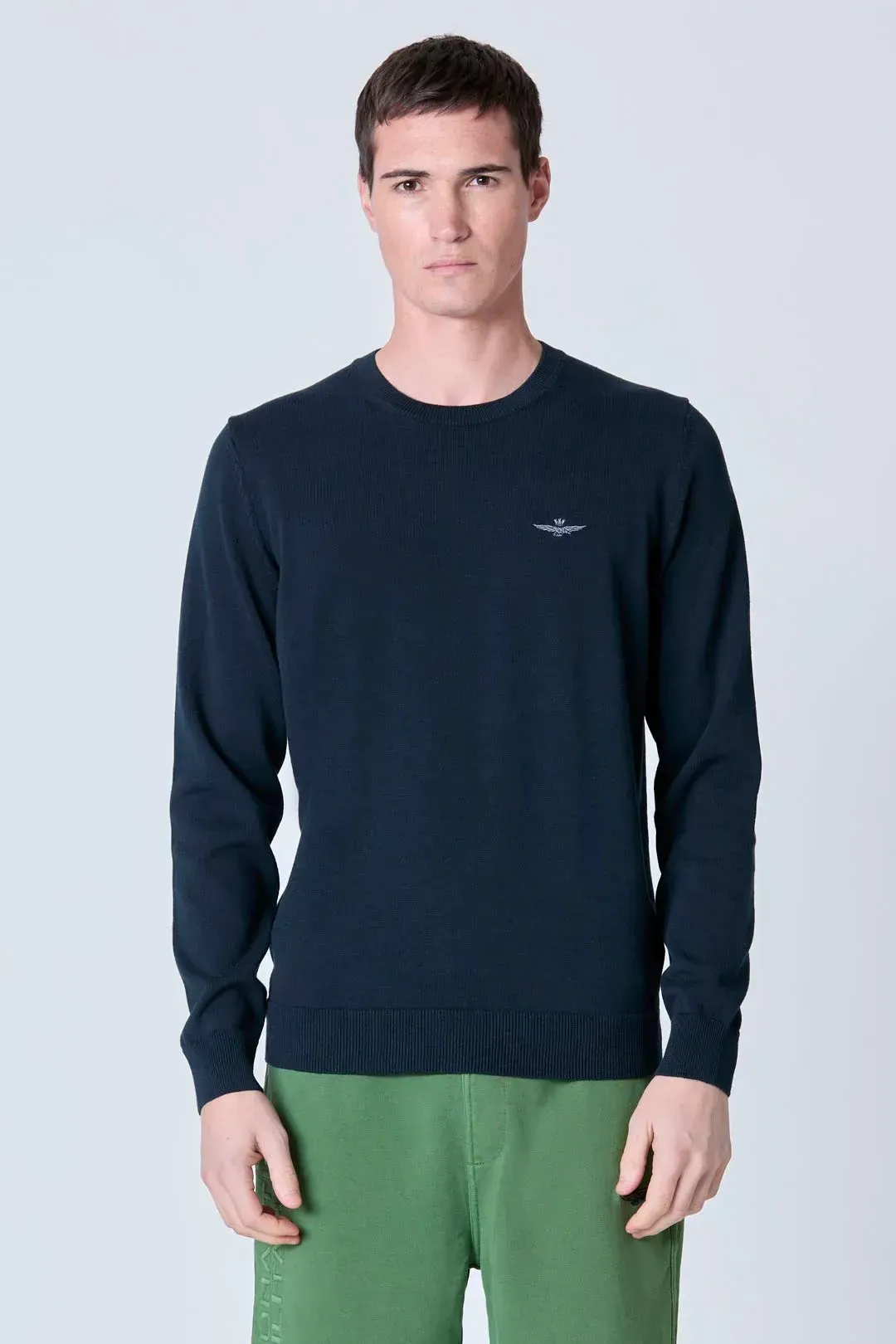 Un uomo che indossa un maglione blu e pantaloni verdi