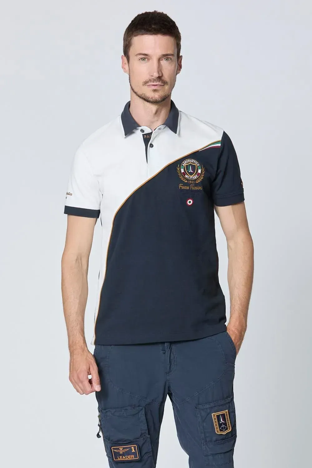 Un uomo indossa una polo blu e bianca e pantaloni cargo blu.