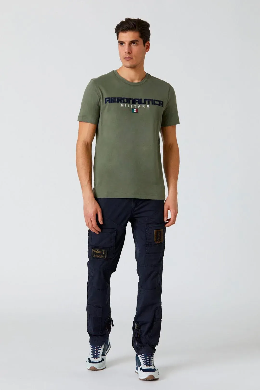 Un uomo che indossa una maglietta verde e pantaloni blu