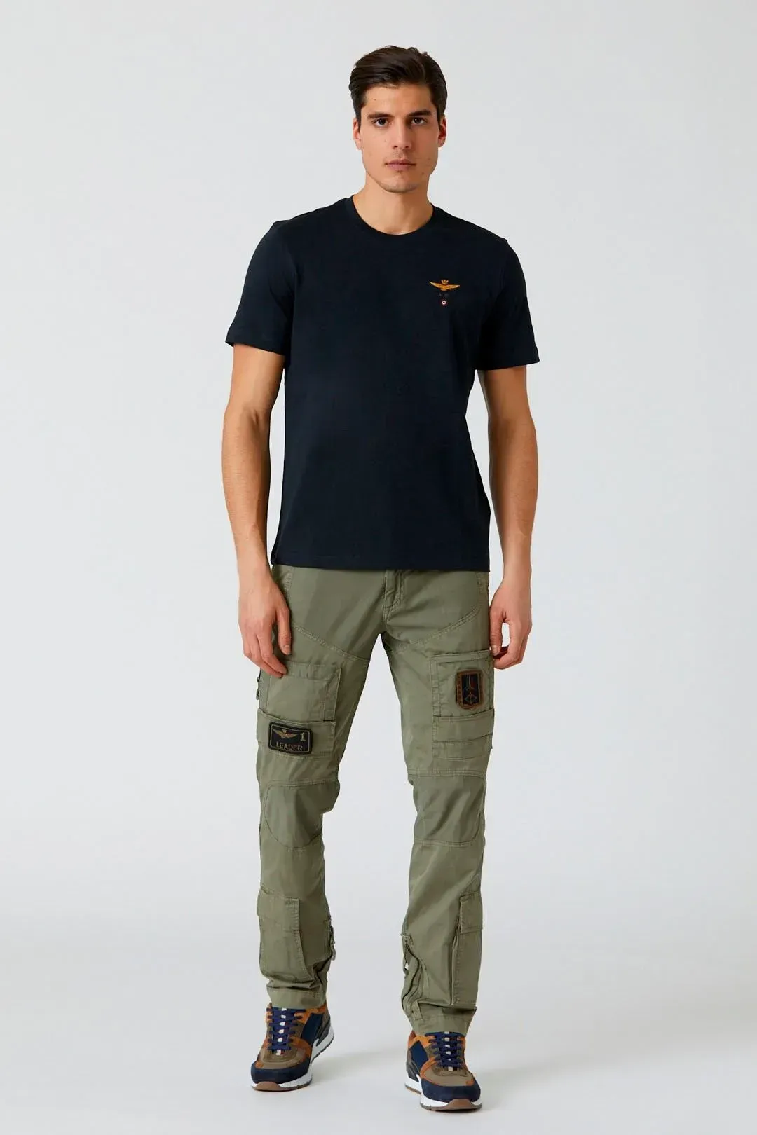 Un uomo indossa una maglietta nera e pantaloni cargo verdi.