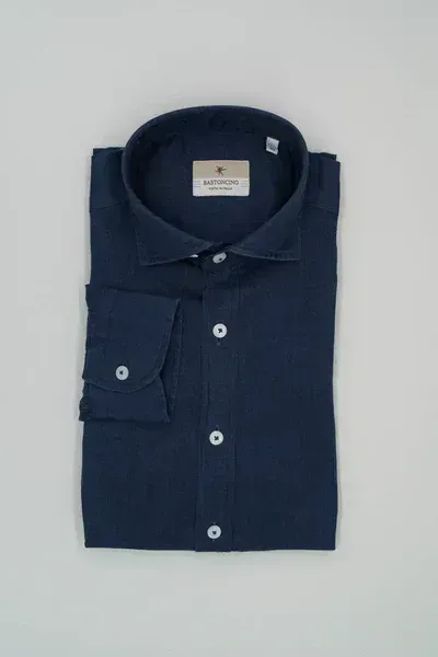 Una camicia blu con bottoni bianchi è appoggiata su una superficie bianca.