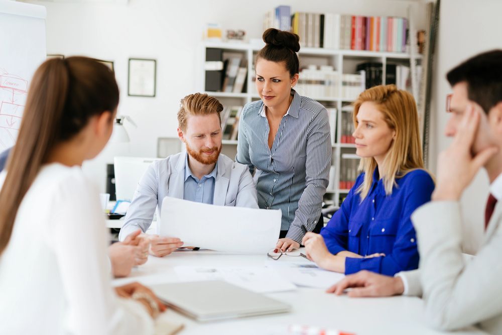 Equipo de negocios en una reunión, revisando documentos en una mesa en una oficina luminosa.