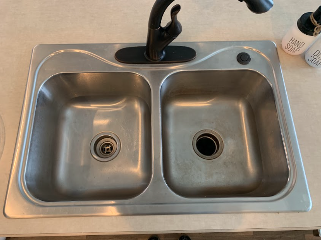Top-down view of a stainless steel double sink with a black faucet and empty basins.
