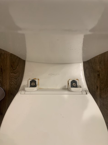 Top-down view of a white toilet seat with wood paneling on both sides.