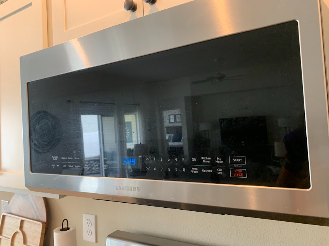 Black over-the-range microwave mounted above a kitchen counter with stainless steel trim
