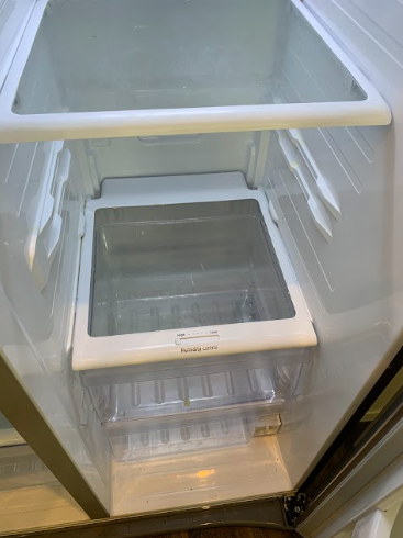 Empty refrigerator interior with glass shelves and drawers, seen from the open door