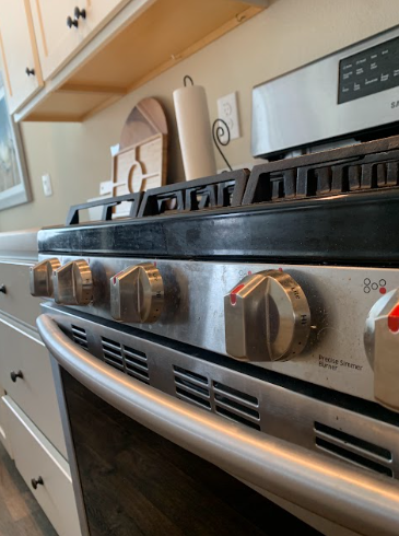 Close-up of a stainless steel gas stove with oven knobs and burners in a kitchen
