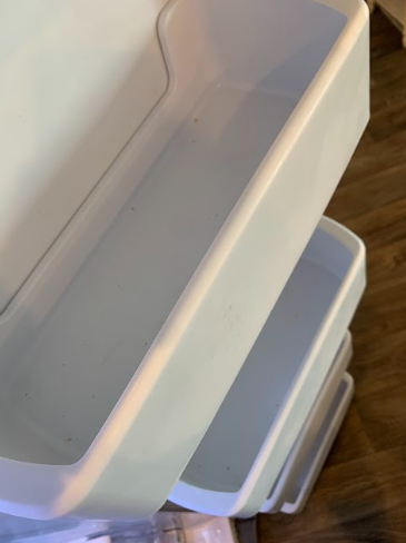 Stacked white plastic storage bins on a wooden floor.