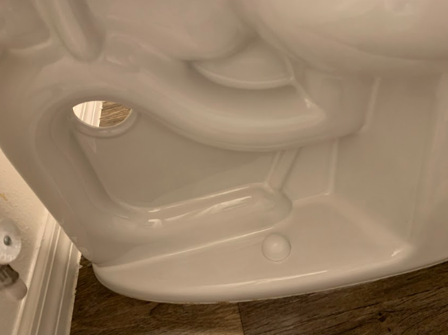 Close-up of the inside of a white plastic appliance door with molded compartments and a circular vent opening.