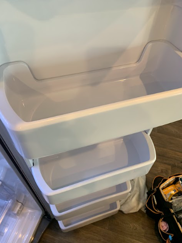 Stacked clear plastic storage bins inside a refrigerator or pantry shelf.