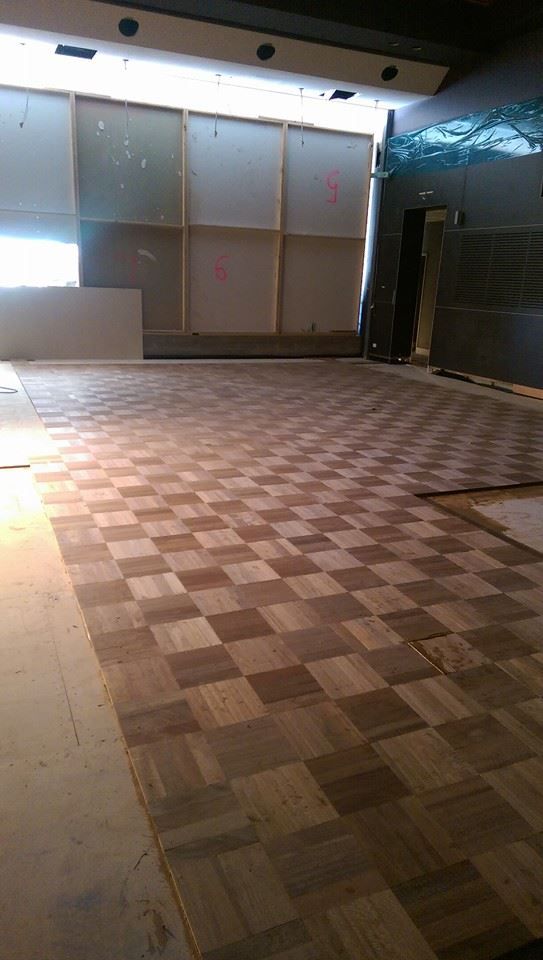A large empty room with a checkered wooden floor.