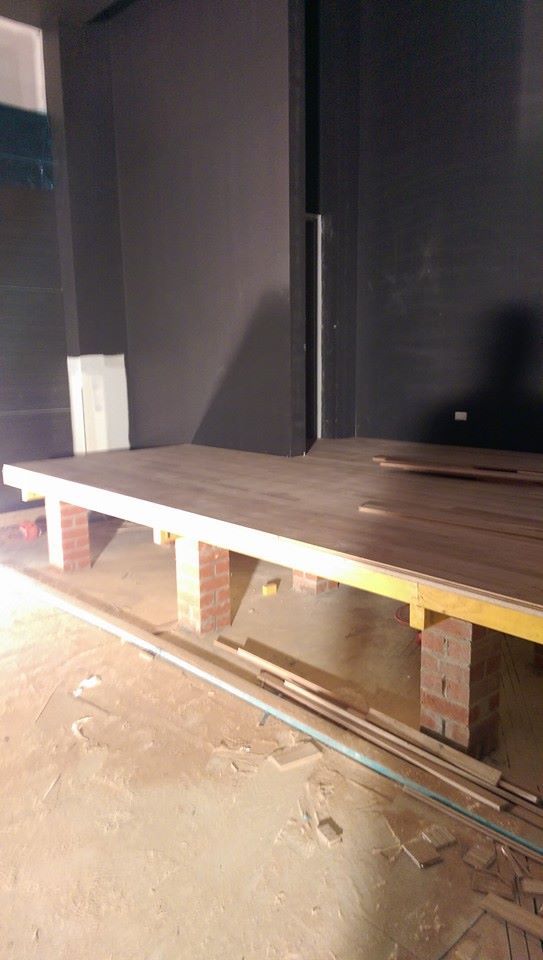 A wooden table is sitting on top of a brick floor in a room.