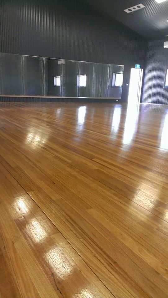A hallway with a wooden floor and a kitchen in the background.