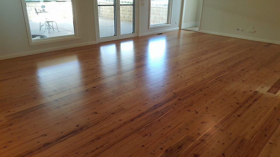 A living room with a wooden floor and sliding glass doors.