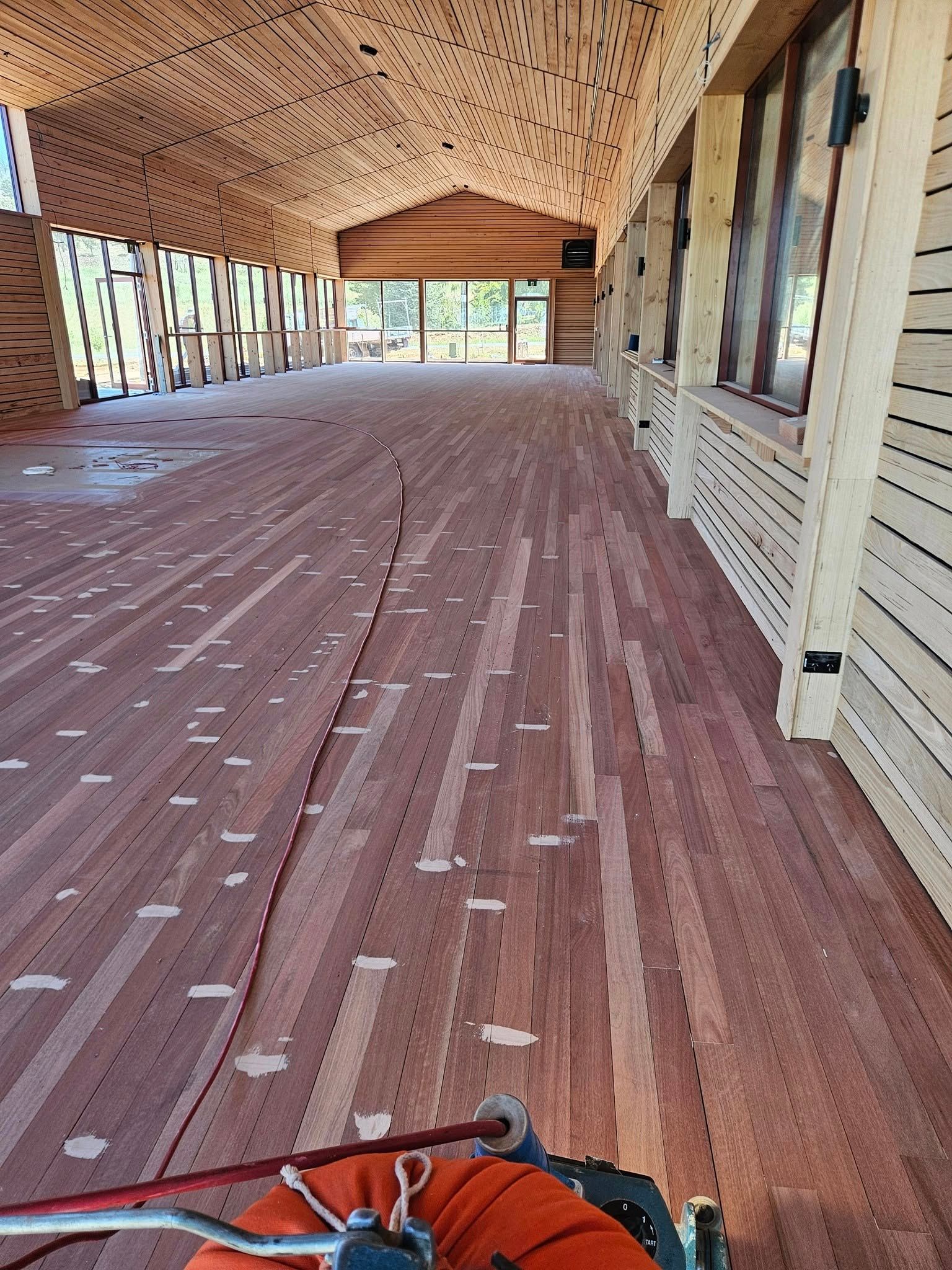 A long hallway with a wooden floor in a building under construction.
