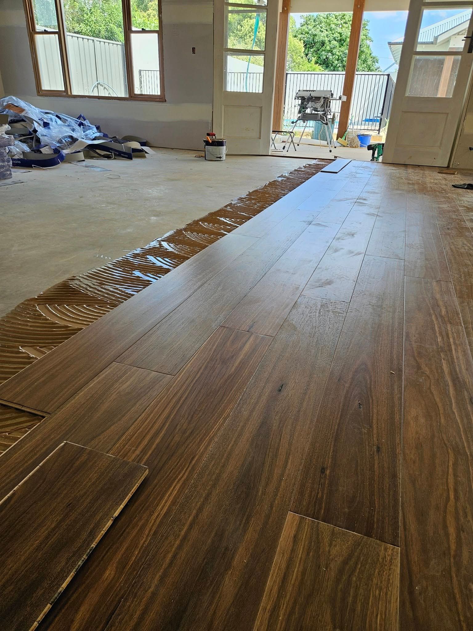 A wooden floor is being installed in a living room.