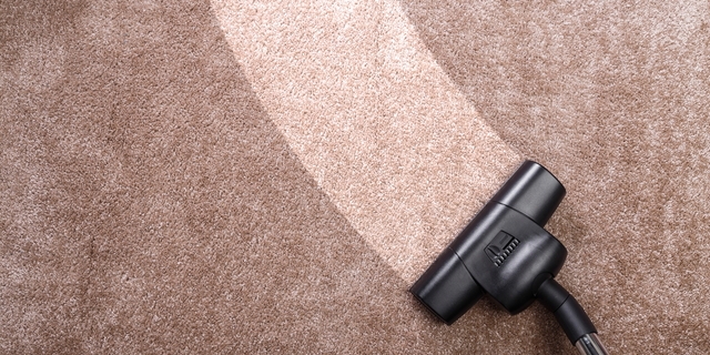 Vacuum cleaner cleaning a brown carpet, leaving a clean trail.
