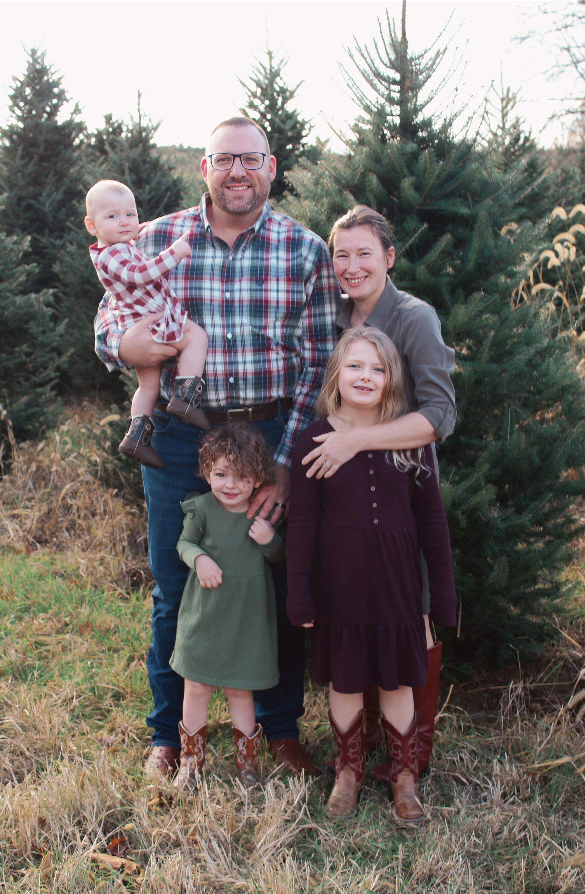 Woman and man stand in front of flowering tree, woman in blue dress and jacket, man in suit.