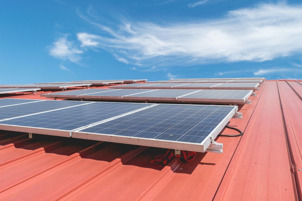 Solar Panels Installed On A Red Metal Roof Against A Blue Sky — GSA Group In Garbutt, QLD