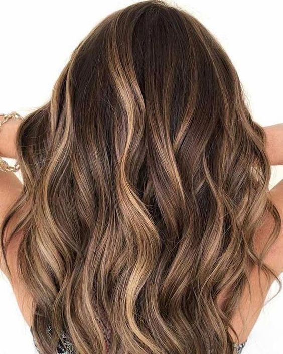 Cabello castaño ondulado con reflejos rubios.