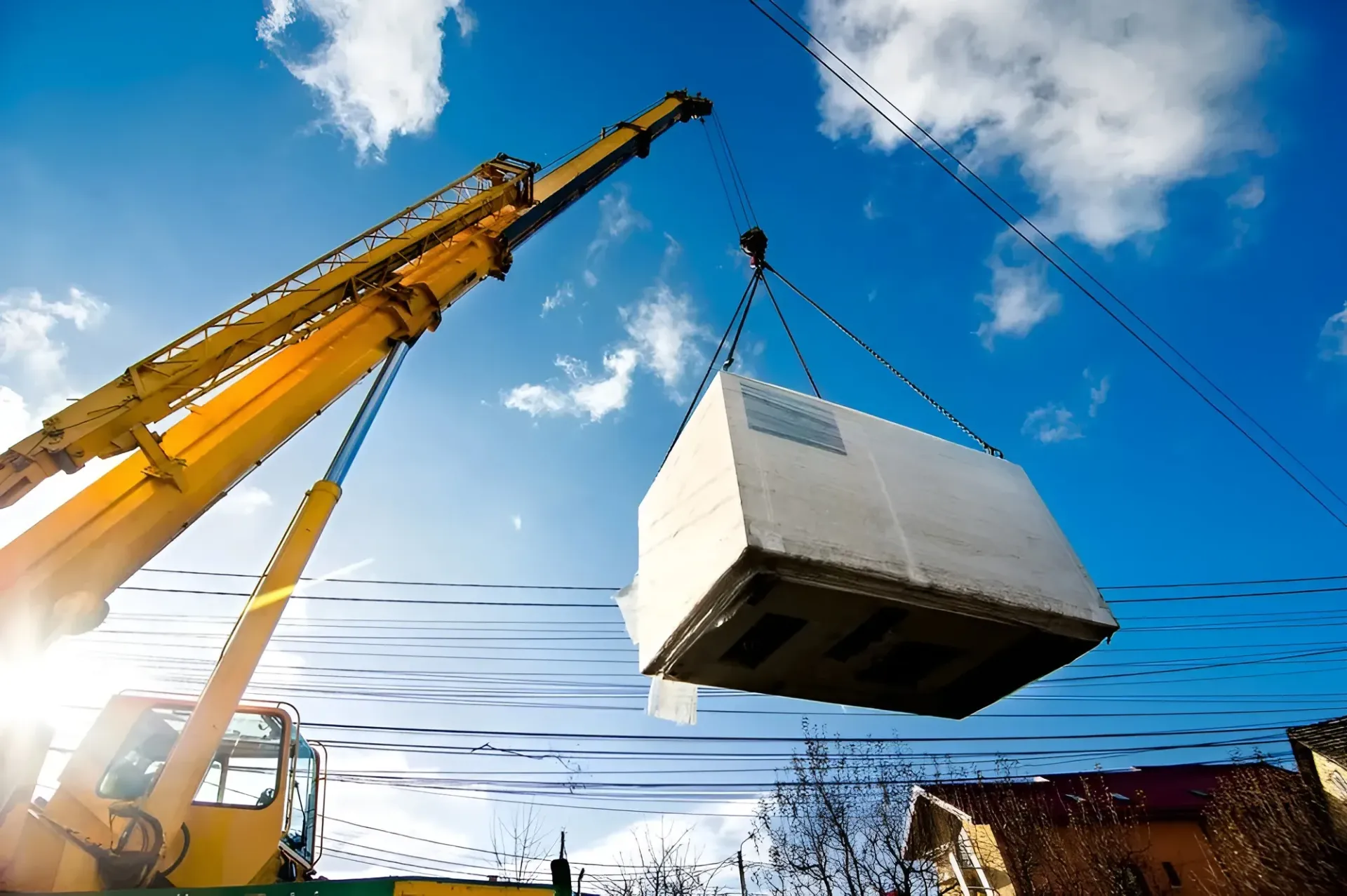 Yellow Crane Lifting a Large, White Structure Against a Bright Blue Sky — Mareeba Crane Hire In Mareeba, QLD