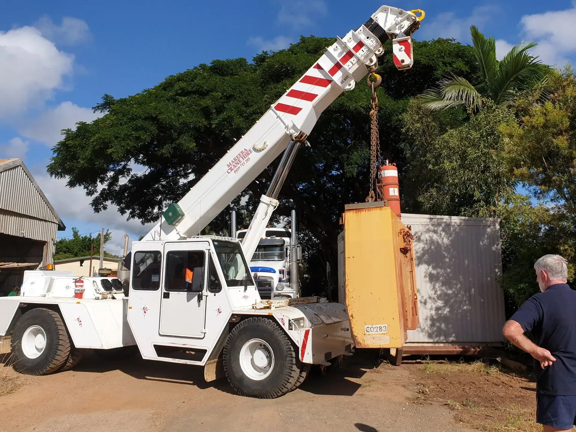 A Worker Watches a Crane Lift Metal Barriers on a Cloudy Day — Mareeba Crane Hire In Mareeba, QLD