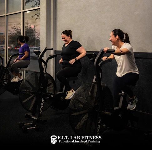 Three women are riding exercise bikes in a gym.