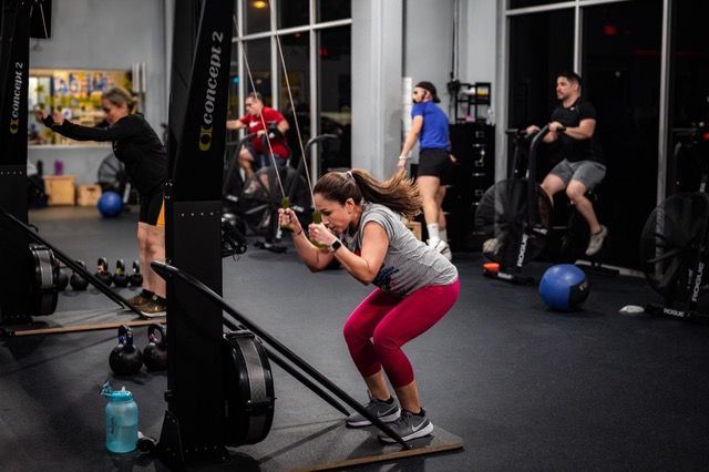 A woman is squatting on a machine in a gym.