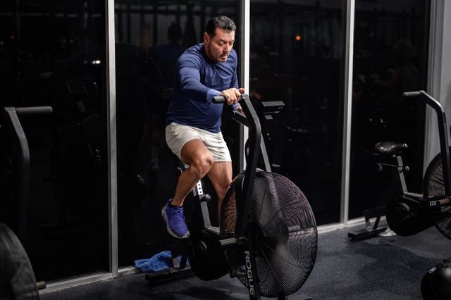 A man is riding an exercise bike in a gym.