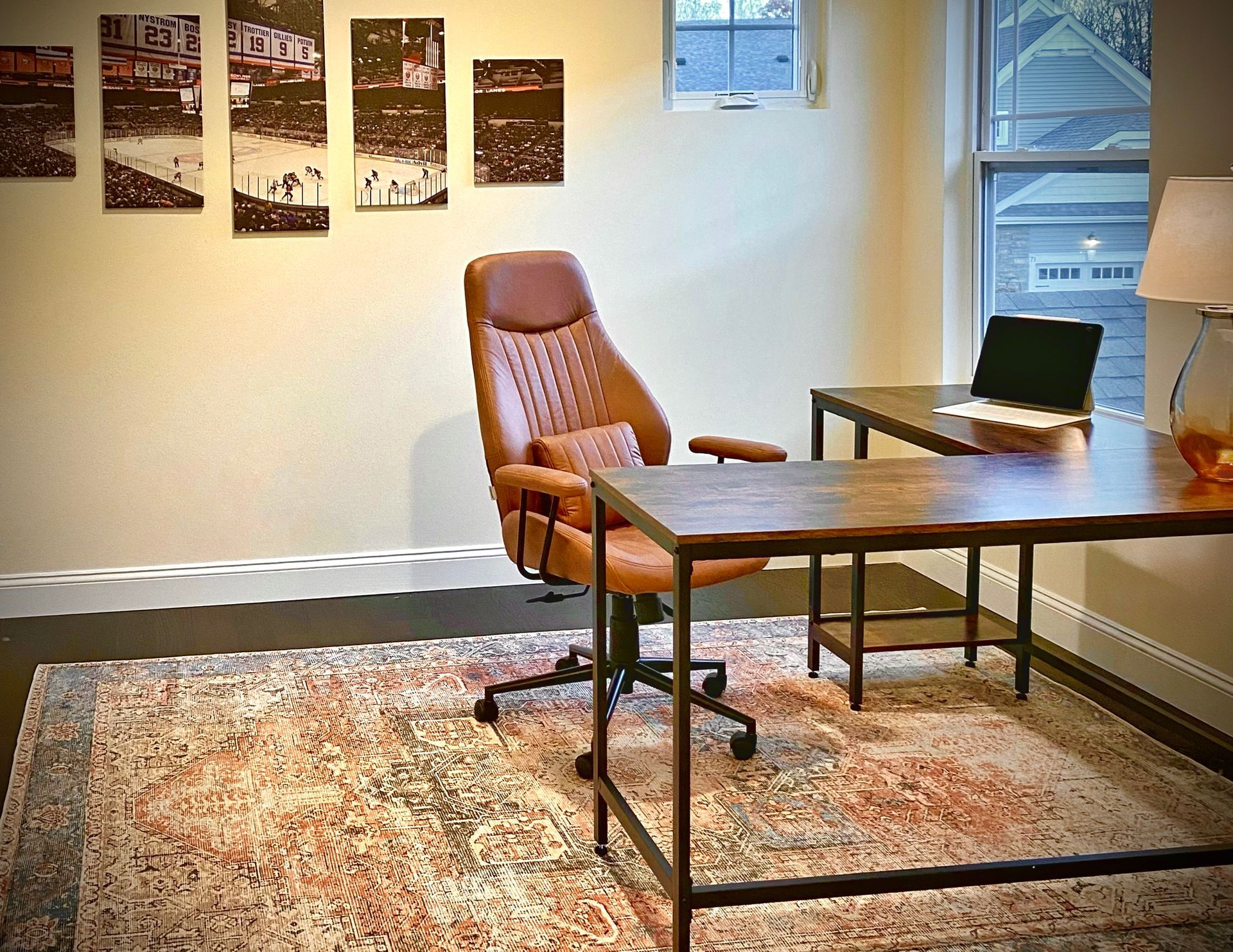 Home office with a brown leather chair, two desks, and a patterned rug. NY Islanders 5 panel art on wall. By Robin Bradley Designs 