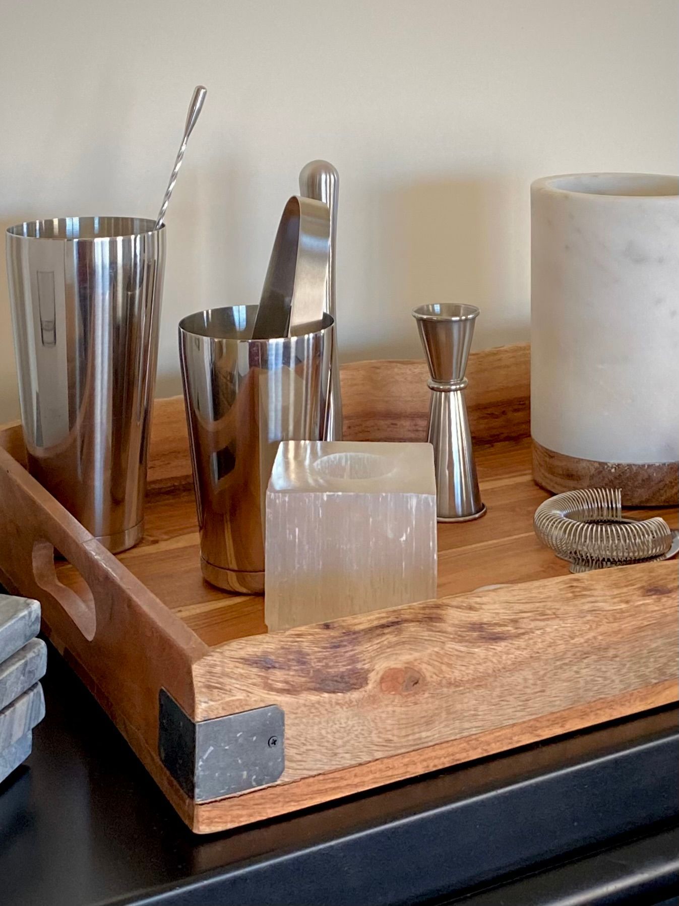 A bar tray with bar tools, a cube, and candle holder on a wooden table...
By Robin Bradley Designs 