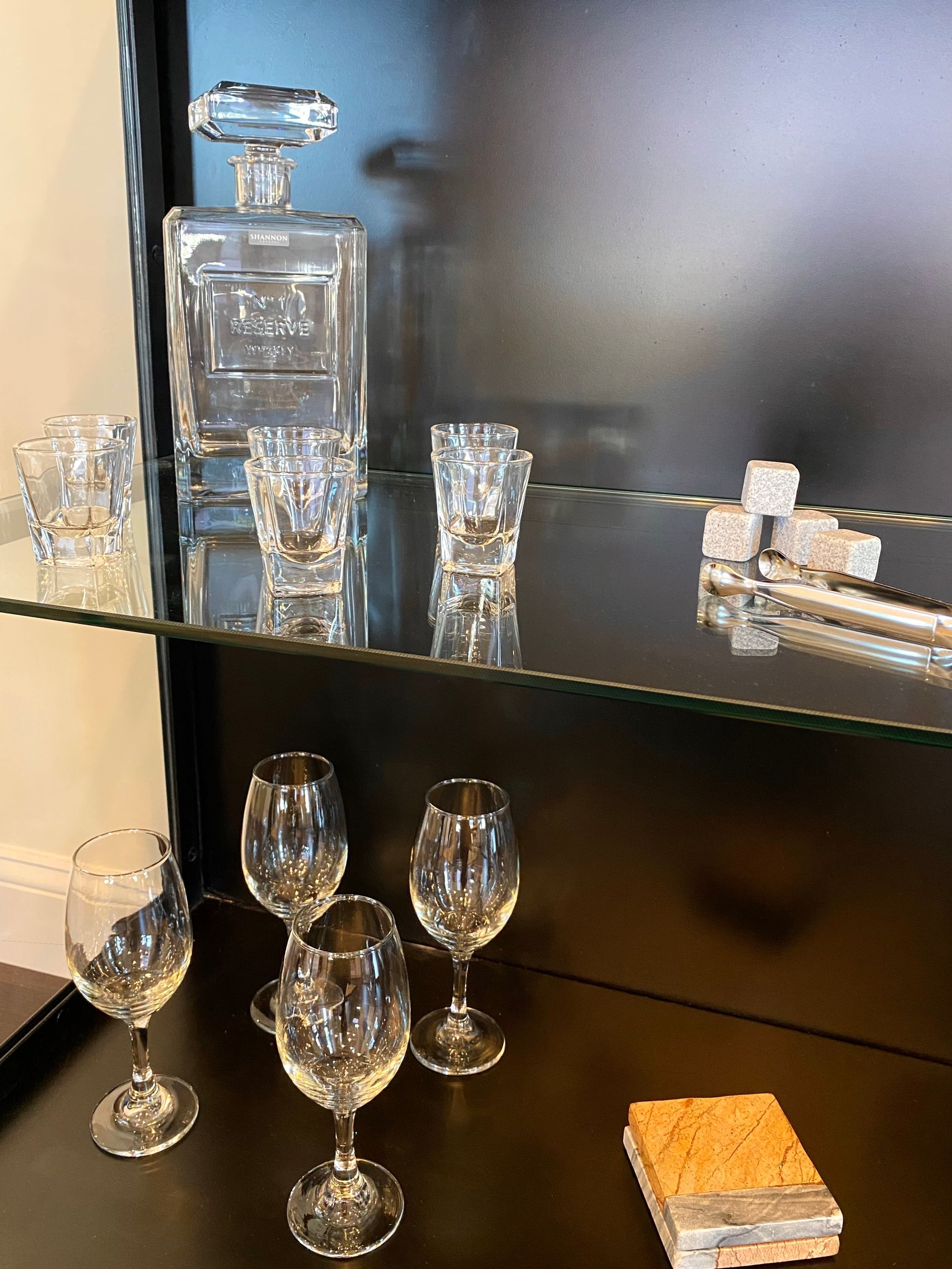 Crystal barware on display in a black cabinet, including decanter, shot glasses, wine glasses and ice cubes.
By Robin Bradley Designs 