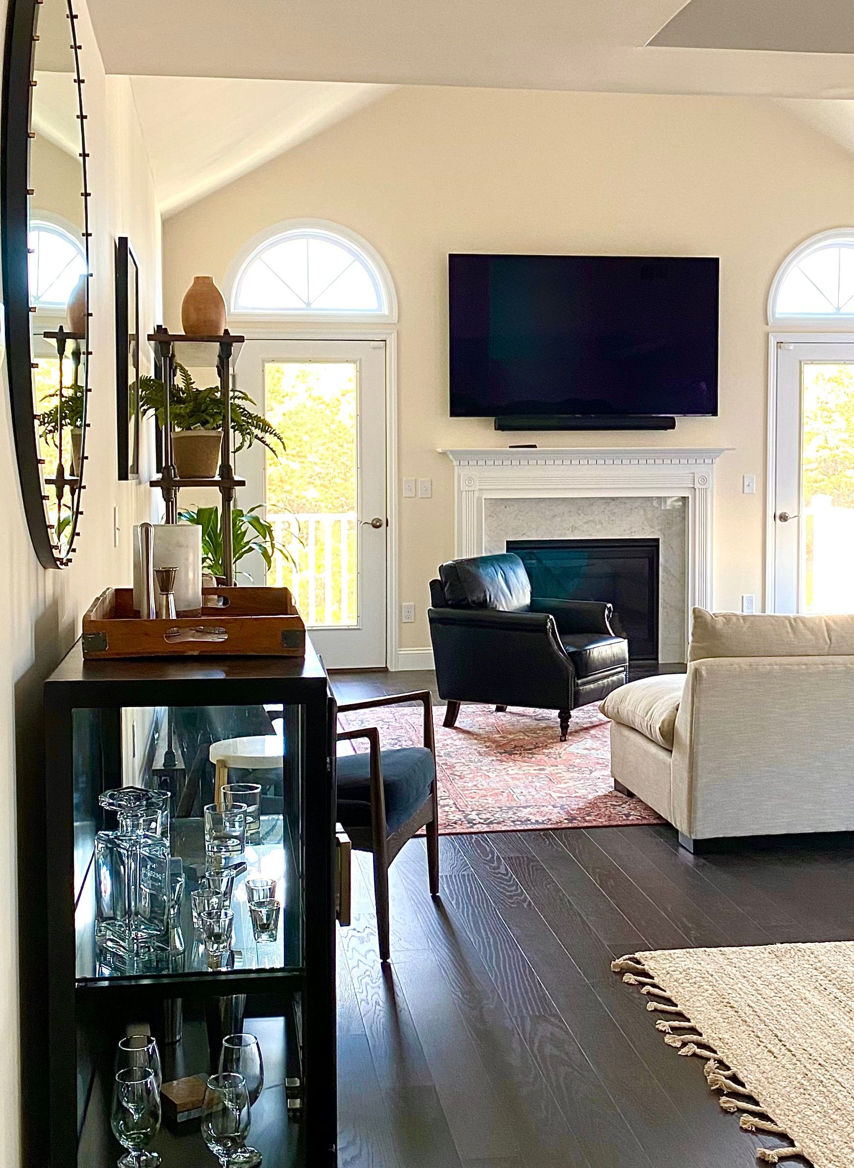 Living room design by Robin Bradley Designs — dark wood floors, warm fireplace, and balanced contrast with a black TV above.