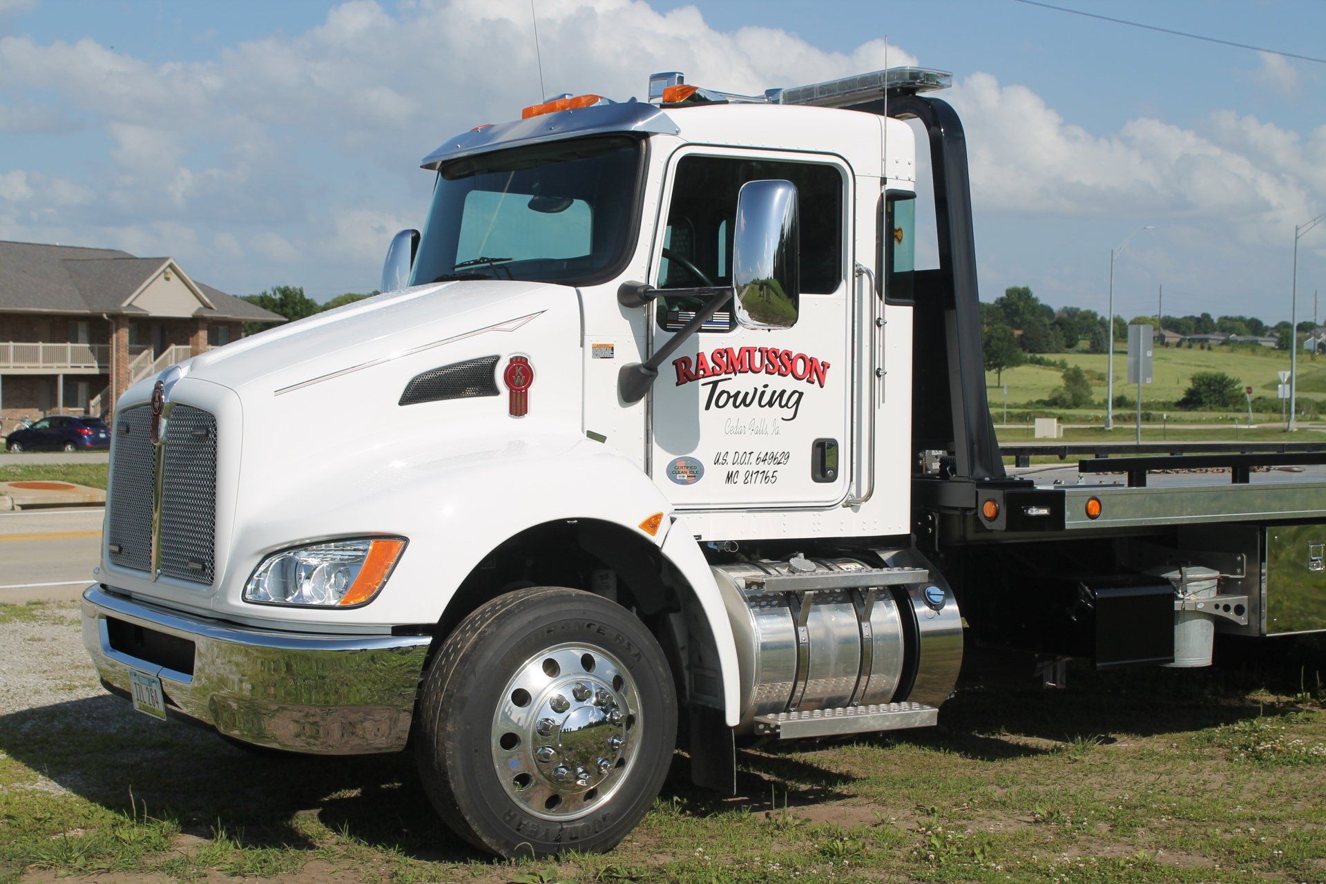 A white tow truck is parked in a grassy field